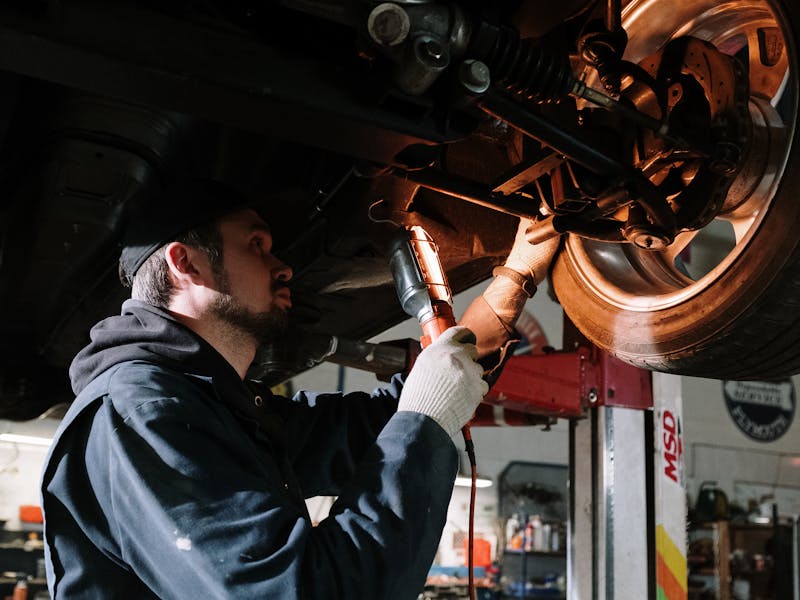 Mechanic examining vehicle undercarriage during pre-purchase inspection